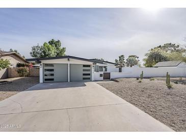 Charming single-story home featuring a modern gray garage door and a xeriscaped front yard with desert plants at 2925 E North Ln, Phoenix, AZ 85028