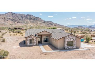 Stunning single-story home with stone accents and desert landscaping against a backdrop of picturesque mountains at 6107 E Lone Mountain Rd, Cave Creek, AZ 85331