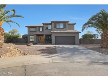 Two-story home boasts desert landscaping, a two car garage, and mature palm trees at 6993 S Sharon Ct, Chandler, AZ 85249