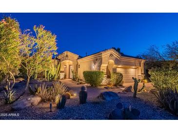 Warm lighting showcases a desert-landscaped home with neutral tones and well-manicured shrubs at twilight at 9431 N Summer Hill Blvd, Fountain Hills, AZ 85268