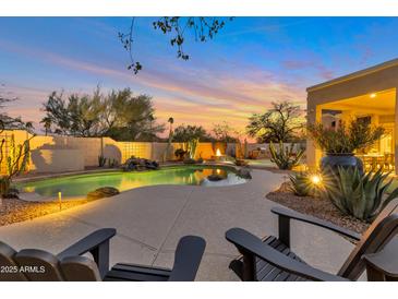 Stunning outdoor pool area with a waterfall feature, fire pit, and lounge chairs at sunset at 9727 E Presidio Rd, Scottsdale, AZ 85260