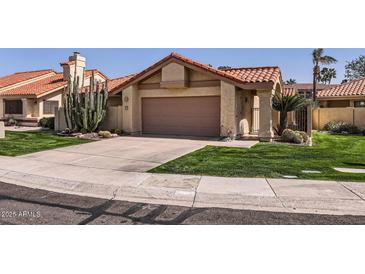 Charming single-story home featuring a two-car garage and desert landscaping at 9803 N 100Th Pl, Scottsdale, AZ 85258