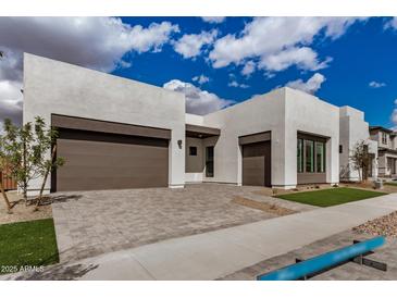 Contemporary home featuring a three car garage and a well-manicured lawn at 10308 E Utah Ave, Mesa, AZ 85212