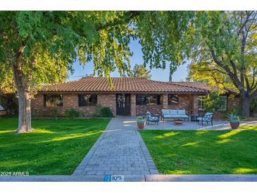 Charming brick home featuring a well-manicured lawn and a cozy outdoor seating area, perfect for relaxing at 105 E Claremont St, Phoenix, AZ 85012