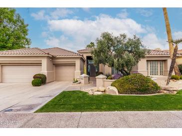 Charming single-story home featuring a well-maintained lawn, desert landscaping and a three car garage at 11664 E Del Timbre Dr, Scottsdale, AZ 85259