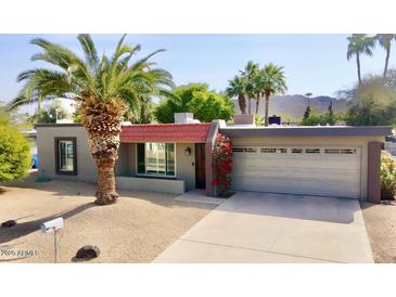 Charming single-story home featuring a desert landscaped yard with a large palm tree and an attached two-car garage at 4001 E Cannon Dr, Phoenix, AZ 85028