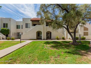 Inviting exterior view of condo with lush lawn, mature shade trees, and path to the unit at 4730 W Northern Ave # 1158, Glendale, AZ 85301