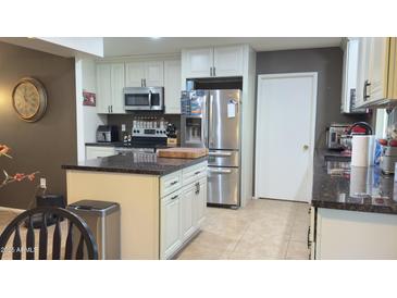 Bright kitchen featuring white cabinetry, stainless steel appliances, granite counters, and tile floors at 9814 W Shasta Dr, Sun City, AZ 85351