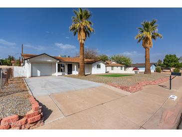 Charming single-story home featuring a well-manicured lawn and inviting curb appeal with palm trees in front yard at 1006 E Weber Dr, Tempe, AZ 85288