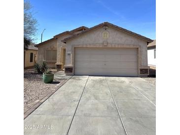 Charming single-story home with a two-car garage, neutral stucco, concrete driveway and desert landscaping at 1606 S 226Th Dr, Buckeye, AZ 85326