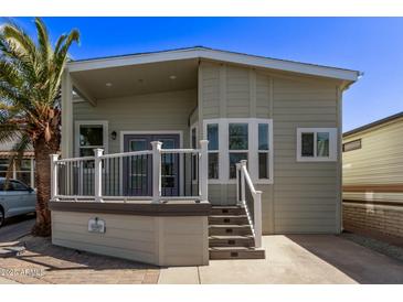 Charming exterior featuring a well-maintained yard, a covered porch with white railings, and mature landscaping at 632 Aero Rd, Mesa, AZ 85205