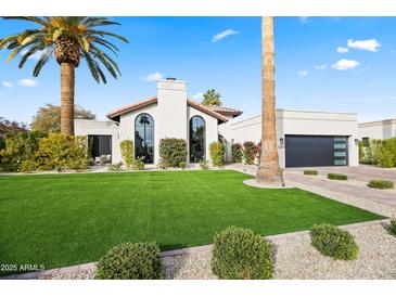 Charming home showcasing a lush lawn, mature palm trees, and modern architectural design at 8206 E Del Camino Dr, Scottsdale, AZ 85258