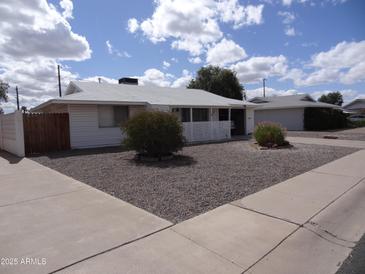 Charming single-story home with a well-maintained gravel front yard and a white fence at 10607 W El Rancho Dr, Sun City, AZ 85351