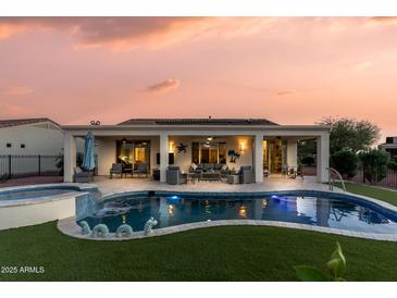 Backyard pool and spa with outdoor living space, covered patio and lush artificial grass at twilight at 13616 W Junipero Dr, Sun City West, AZ 85375