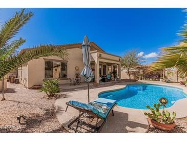 Inviting backyard oasis with a sparkling pool, lounge chairs, and lush landscaping at 45290 W Juniper Ave, Maricopa, AZ 85139