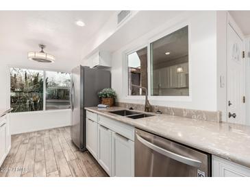 Modern kitchen featuring stainless steel appliances, granite countertops, and white cabinetry at 5142 E Holly St, Phoenix, AZ 85008