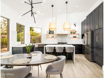 Bright kitchen with island, dining area, stainless steel appliances, and dark cabinets at 6438 E Montreal Pl, Scottsdale, AZ 85254