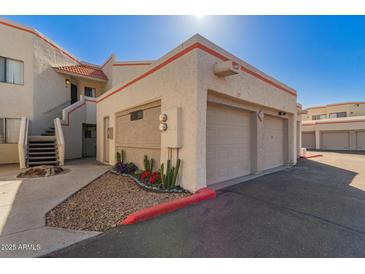 Two-car garage with colorful landscaping, red trim, and stucco exterior at 835 N Granite Reef Rd # 29, Scottsdale, AZ 85257