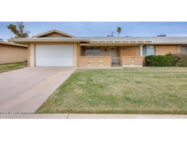 Charming single-story home with a well-manicured lawn and attached garage in a friendly community at 10816 W Hatcher Rd, Sun City, AZ 85351