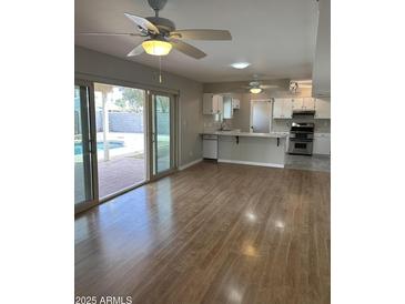 Open concept living room view into kitchen, overlooking pool area with natural light and hardwood flooring at 1172 E Delano Dr, Casa Grande, AZ 85122