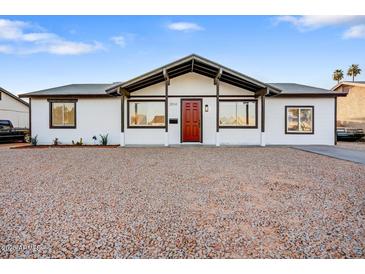 Charming single-story home featuring a red front door and gravel landscaping at 2834 N 65Th Ave, Phoenix, AZ 85035