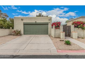 Single-story home featuring a two-car garage, desert landscaping, and a stucco wall with vibrant bougainvillea at 619 E Jensen St # 80, Mesa, AZ 85203