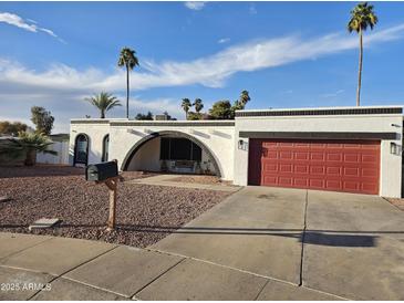 Charming single-story home boasts a red garage door, unique architecture and a well-kept, desert-friendly landscaped front yard at 8227 N 47Th Dr, Glendale, AZ 85302