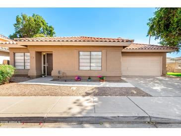 Charming single-story home with a well-maintained yard, mature landscaping, and a two-car garage at 1417 N Brittany Ln, Gilbert, AZ 85233