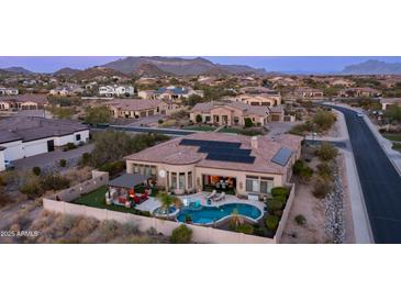 A stunning aerial view of a home, featuring a backyard pool, outdoor kitchen, desert landscape, and solar panels at 2224 N 83Rd Cir, Mesa, AZ 85207
