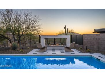 Inviting pool area with a modern fireplace, lounge chairs, and desert landscaping perfect for relaxing evenings at 37200 N Cave Creek Rd # 1035, Scottsdale, AZ 85262