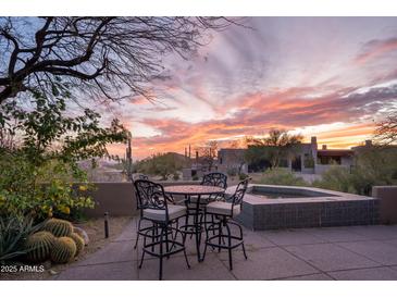 Outdoor patio featuring a dining set and spa, surrounded by desert landscaping and beautiful sunset views at 41353 N 106Th St, Scottsdale, AZ 85262