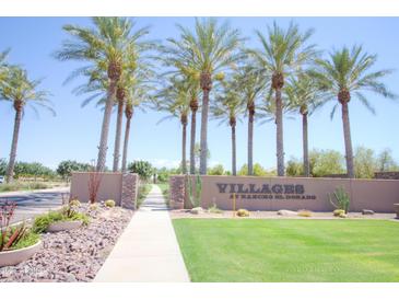 Landscaped community entrance with lush palm trees, desert plants, and attractive signage on a sunny day at 44125 W Cydnee Dr, Maricopa, AZ 85138