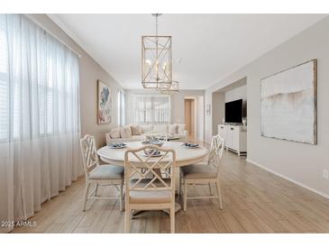 An inviting dining area features a round table and decorative light fixture, seamlessly flowing into the living space at 9910 E Theia Dr, Mesa, AZ 85212