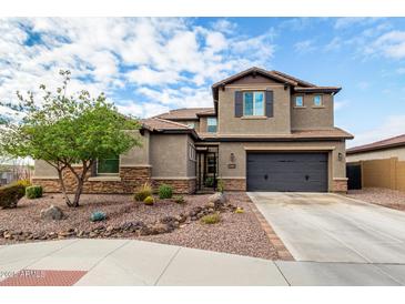 Two-story home featuring neutral stucco siding, a tile roof, dark garage door, and desert landscaping in the front yard at 1525 W Bent Tree Dr, Phoenix, AZ 85085