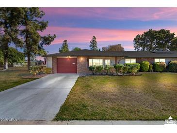 Charming single-story brick home with a well-maintained lawn and a red garage door, ideal for suburban living at 15621 N Lakeforest Dr, Sun City, AZ 85351