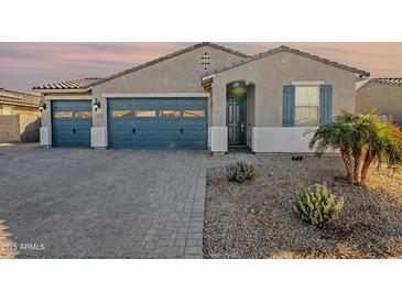 Charming single story home featuring a three car garage, desert landscaping and a covered entryway at 1881 S 223Rd Dr, Buckeye, AZ 85326