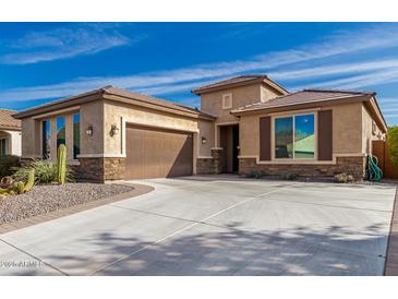 Tan single-Gathering home with a large driveway and desert landscaping with a two car garage and stone accents at 25983 W Escuda Dr, Buckeye, AZ 85396