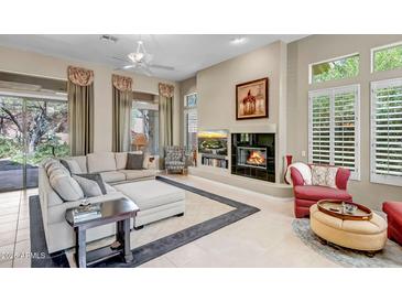 Bright living room featuring a cozy fireplace, plush seating, and elegant window treatments at 3108 W Ravina Ln, Anthem, AZ 85086