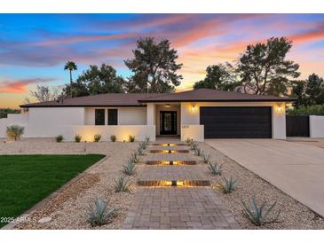 Charming single-story home with illuminated walkway, desert landscaping, and a beautiful sunset at 5819 E Ludlow Dr, Scottsdale, AZ 85254