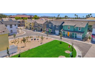 Charming street view of colorful, two-story homes with green lawn and shared public spaces at 16875 N 12Th St # 24, Phoenix, AZ 85022