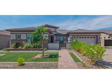 Charming single-story home featuring a well-maintained lawn, brick walkway, and desert landscaping at 18925 W Windsor Blvd, Litchfield Park, AZ 85340