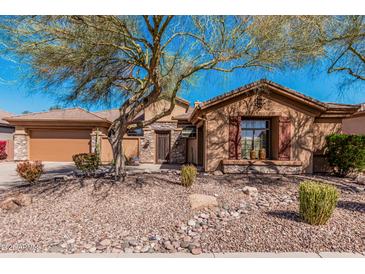 Charming single-story home with desert landscaping and stone accents, shaded by a mature tree at 1926 W Wayne Ln, Anthem, AZ 85086