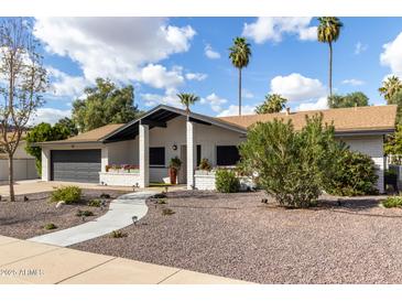 Charming exterior view of a home featuring a well-manicured lawn, flowerbeds, and desert landscaping at 302 W Thunderbird Rd, Phoenix, AZ 85023