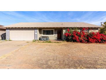 Charming single-story home featuring an attached garage and a beautiful red bougainvillea bush at 323 N Hunt E Dr, Mesa, AZ 85203