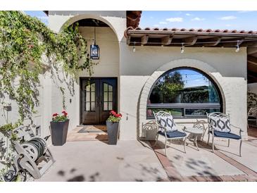 Charming front entrance with stucco walls, arched entryway, double doors, and manicured landscaping at 718 E Tuckey Ln, Phoenix, AZ 85014