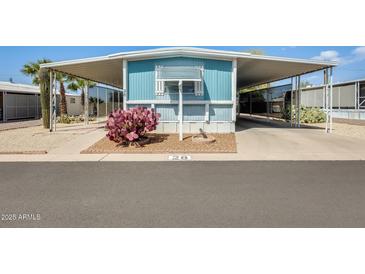 Charming blue home featuring a carport, desert landscaping, and eye-catching magenta cactus in the front yard at 8600 E Broadway Rd # 28, Mesa, AZ 85208