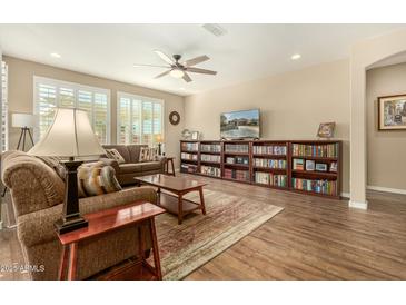 Inviting living room with a ceiling fan, wood floors, and a large bookcase at 21362 N 260Th Ln, Buckeye, AZ 85396