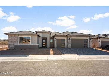 A modern single-Gathering home boasts a three-car garage and desert landscaping at 26817 W Renee Dr, Buckeye, AZ 85396