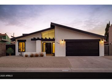 Charming single-story home features a modern design with a black garage door and desert landscaping at 5449 E Cambridge Ave, Phoenix, AZ 85008