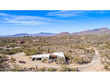 Expansive aerial view of desert home with mountain backdrop, surrounded by mature saguaro cacti and desert vegetation at 8115 E Paint Pony Dr, Carefree, AZ 85377